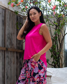 Woman wearing a bright pink top and floral skirt outdoors.