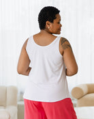 Woman wearing a white tank top and red pants in a living room setting