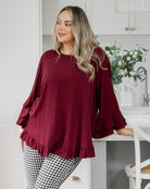 Woman wearing a burgundy top and checkered pants in a kitchen setting