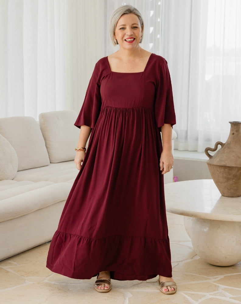 Woman wearing a burgundy dress in a living room setting