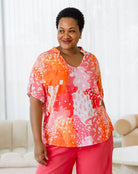 Woman wearing a colorful blouse and pink pants in a living room setting