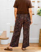 Person wearing leopard print pants and a brown shirt in a home setting.